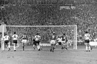 Bobby Charlton, number nine, looks on as Martin Peters, number 16, scores in the 1966 World Cup final