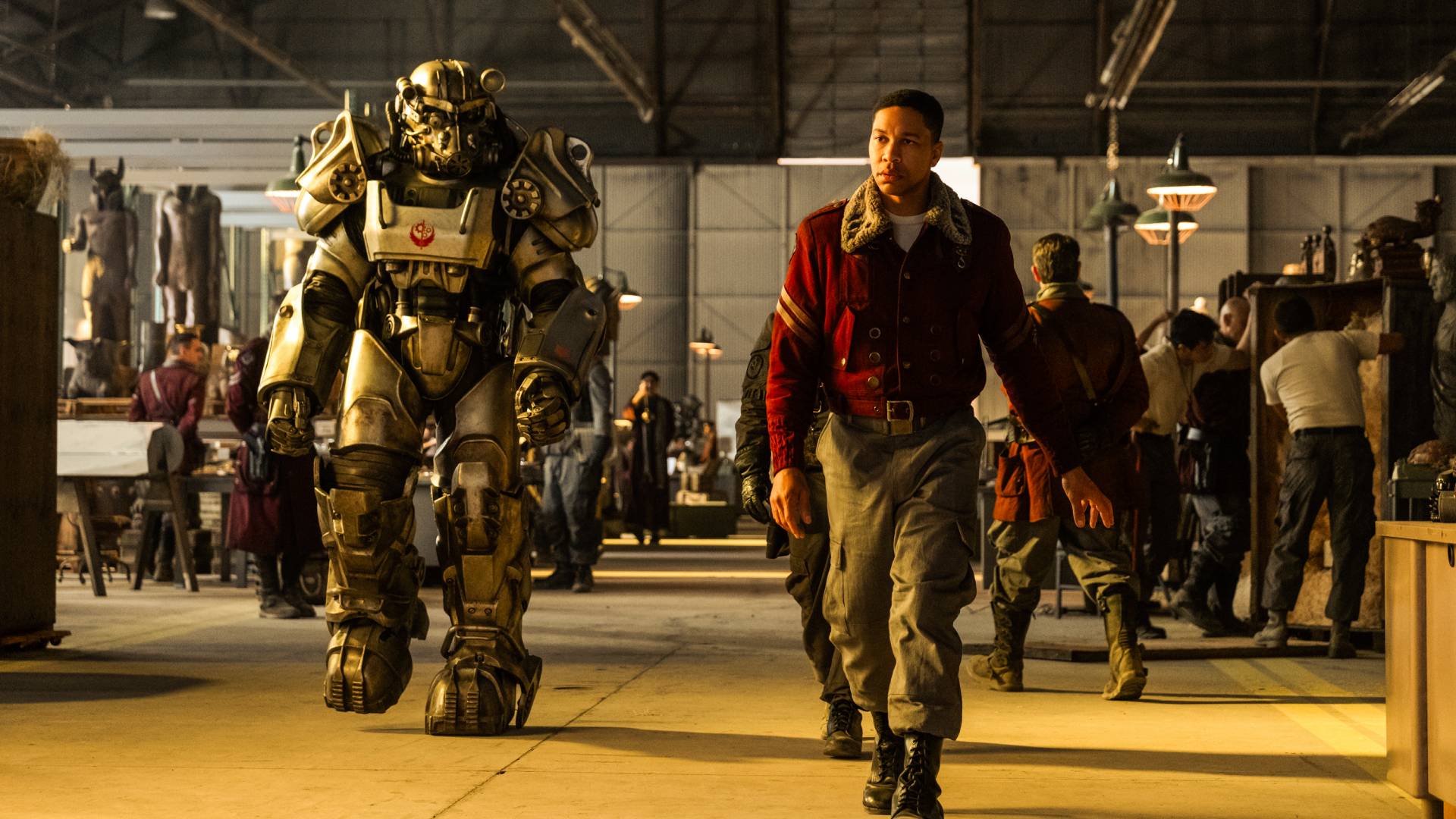 Aaron Moten as Maximus, walking through a hangar next to a person in a suit of power armor