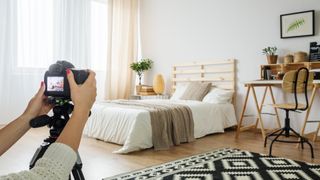 person taking a picture of their modern bedroom with bed and desk, an expert spring cleaning tip