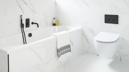 Bathroom makeover. Contemporary monochrome and streamlined bathroom with marble wall tiles and black accents. Bathroom renovation in a five bedroom detached house in East Sussex, home of Jennie Roe.