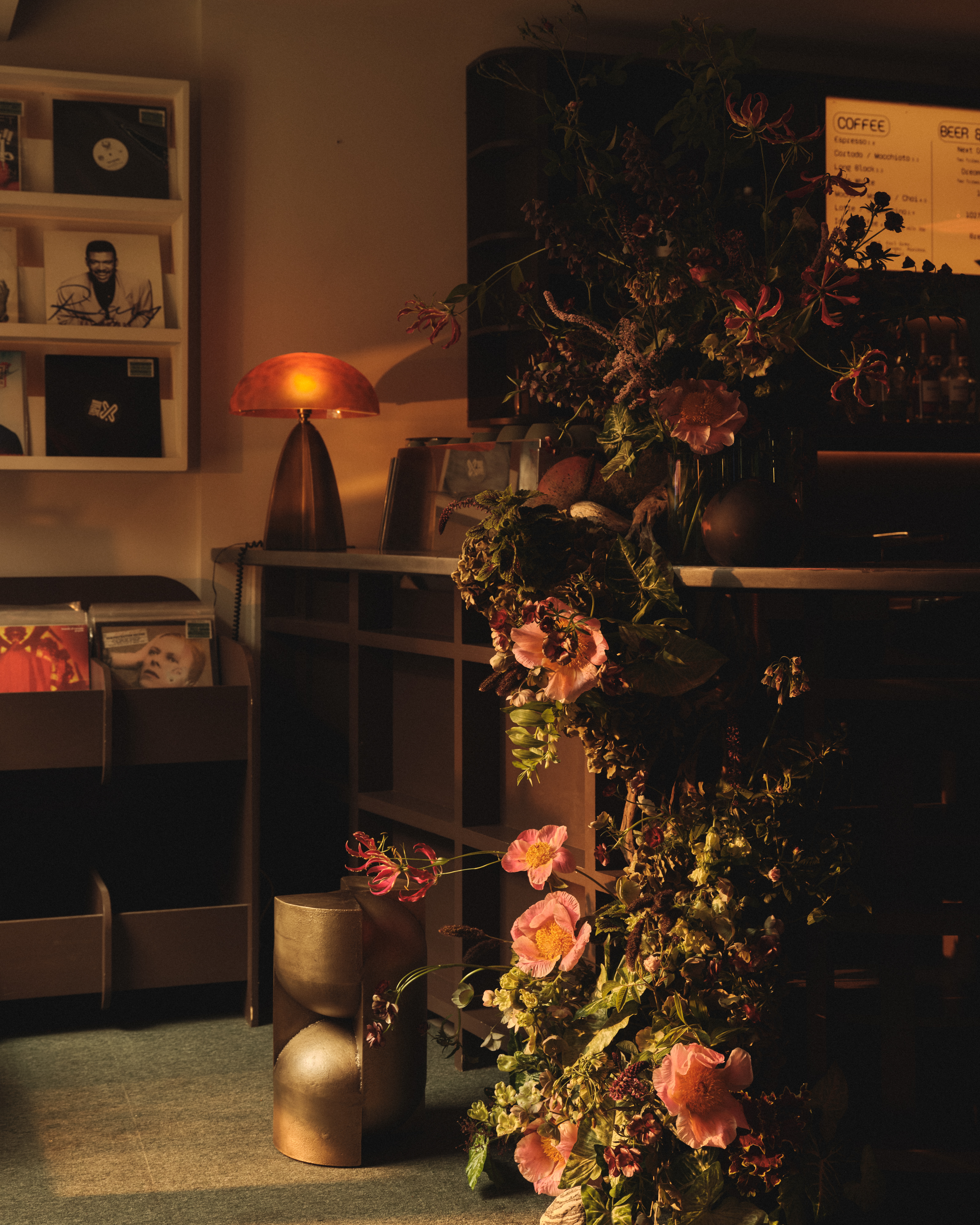 A listening bar decorated with golden light, chrome stools and coffee tables, mushroom-shaped lamps, and wooden cabinetry.