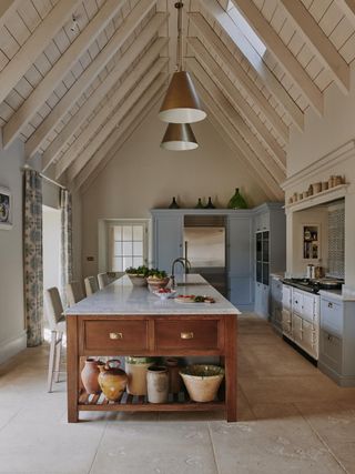 A kitchen with a vaulted ceiling, powder blue cabinetry, and a wooden kitchen island with a marble top