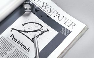 Newspaper with black font and ink pen placed on top