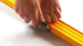 Pair of hands cutting plasterboard with a knife