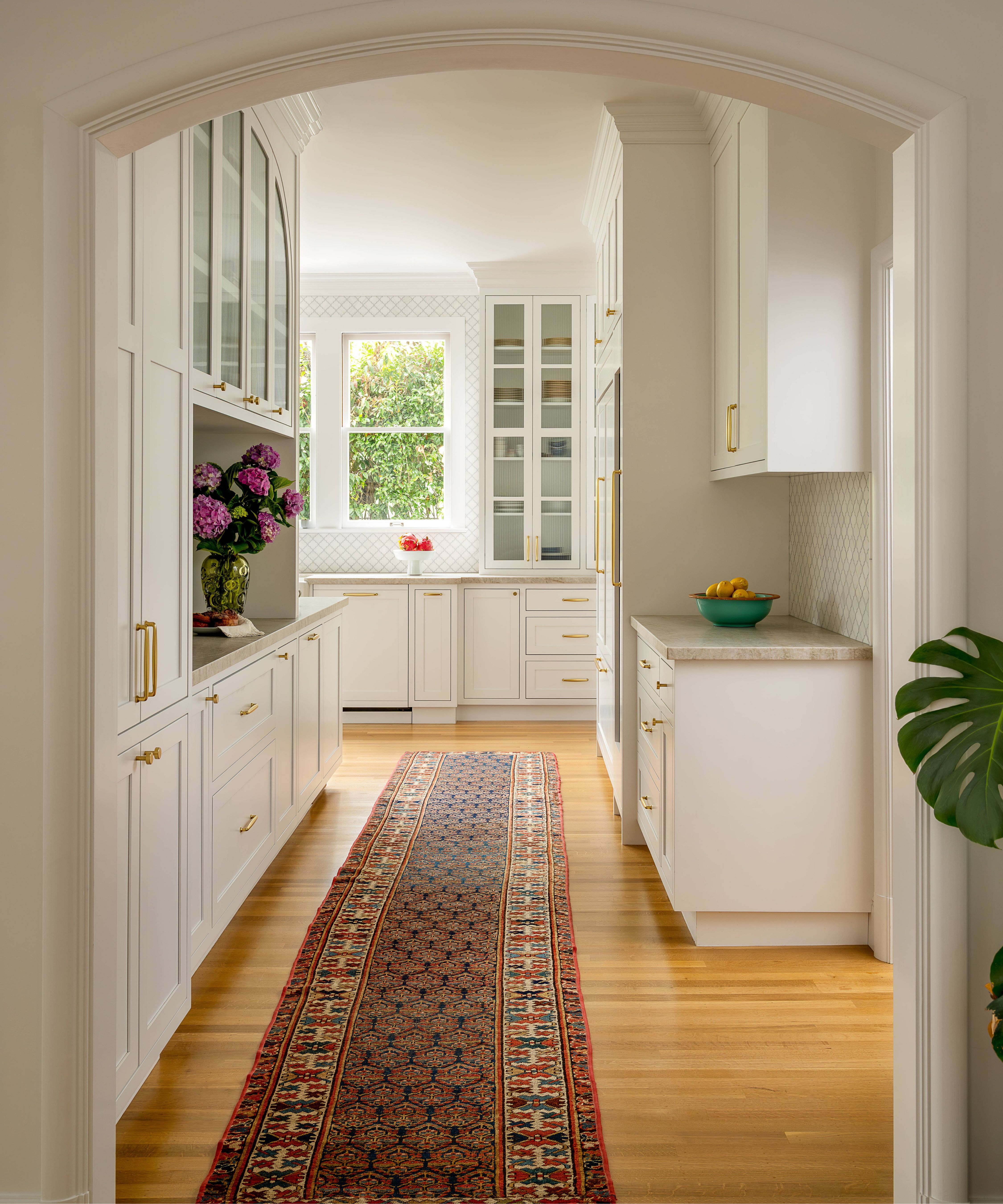 a kitchen entry corridor with pantry cabinetry and a long vintage rug