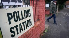 Man walks out of polling station in Gorton and Denton, behind sign saying "polling station"