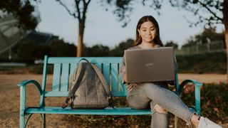 Woman sat on bench using a laptop