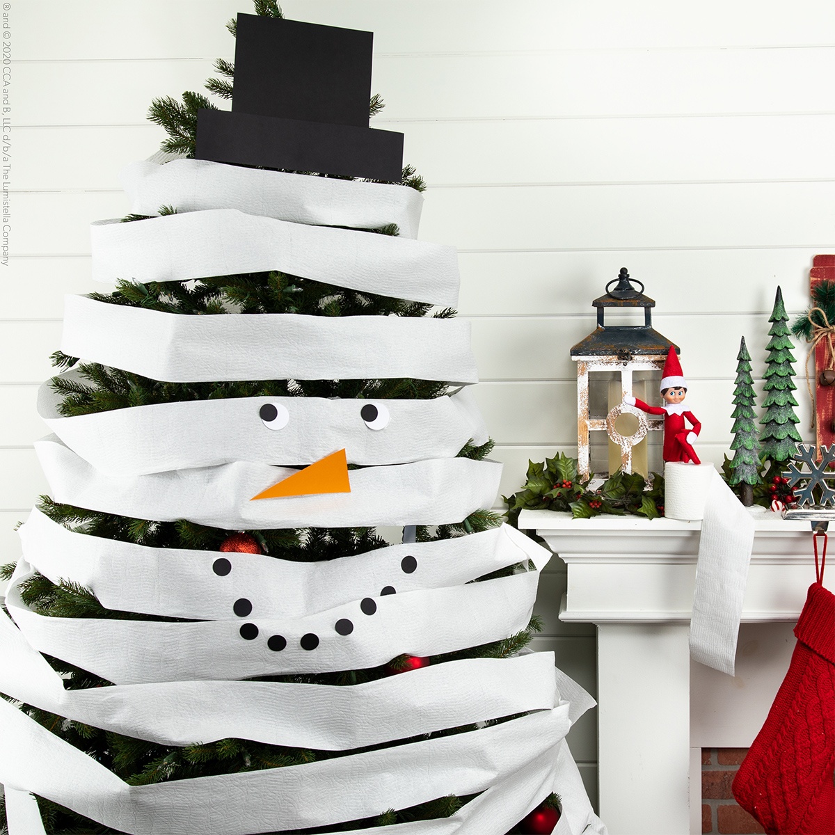 a Christmas tree covered in toilet roll with an Elf on the mantelpiece next to it, one of our Elf on the Shelf ideas