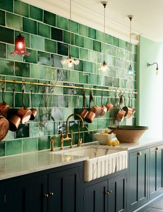 Green kitchen with glazed wall tiles and vintage pendant lights