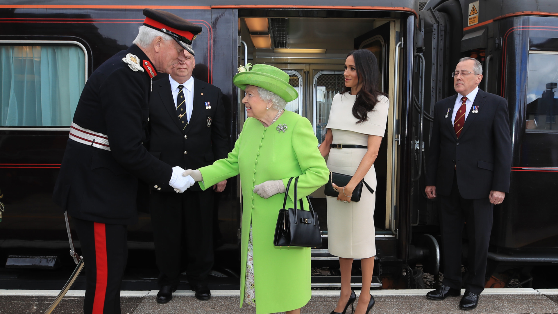 Queen Elizabeth and Meghan Markle standing next to the royal train