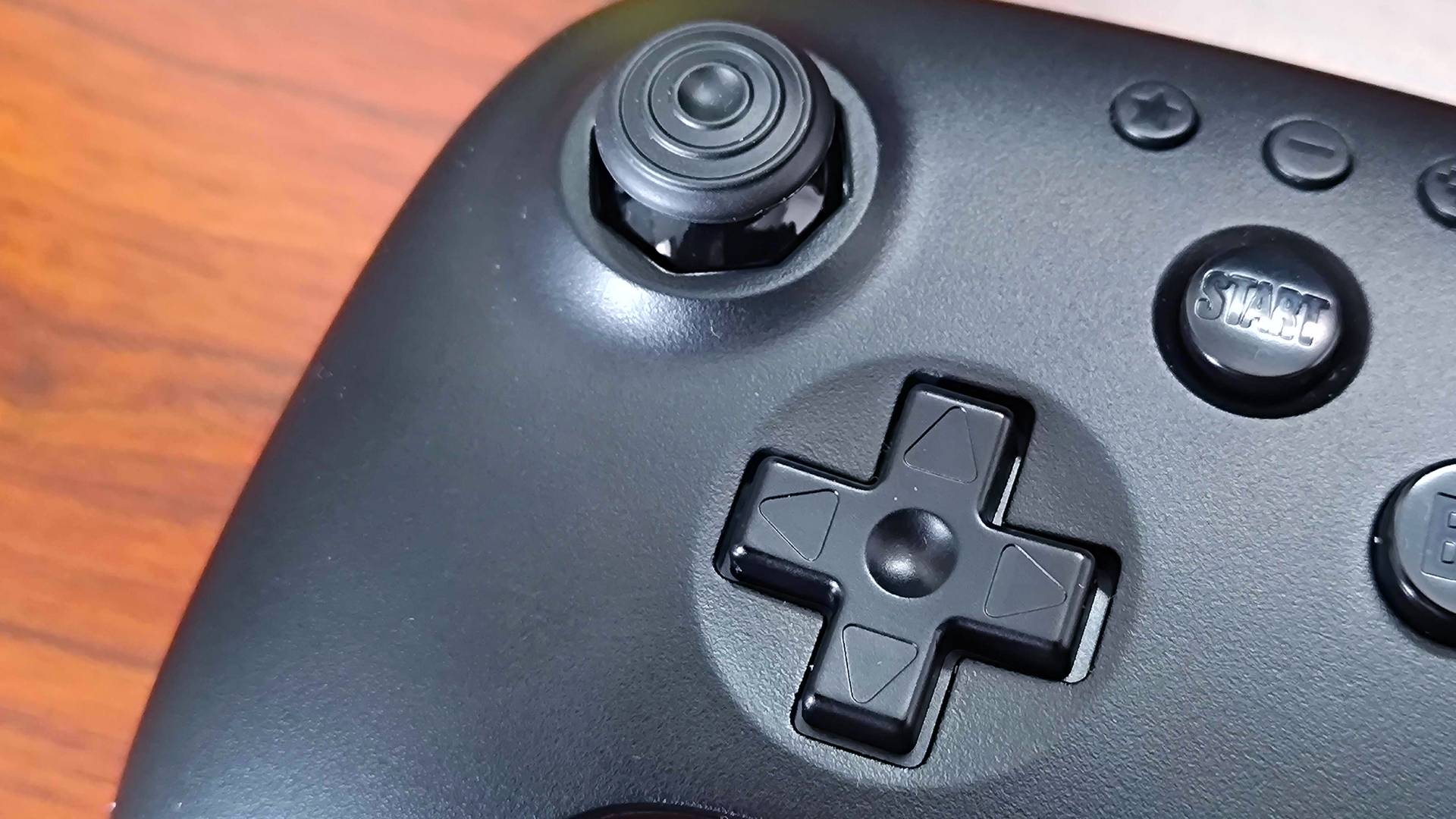 Close up of 8Bitdo N64 Bluetooth controller thumbstick and d-pad with controller sitting on woodgrain surface.