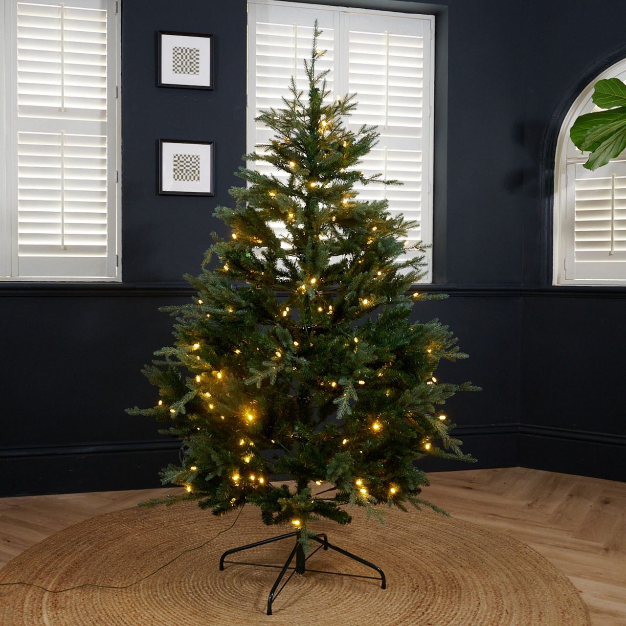 Habitat's 6ft Pre lit Upswept Mixed Tip Christmas Tree set up in a black-painted living room