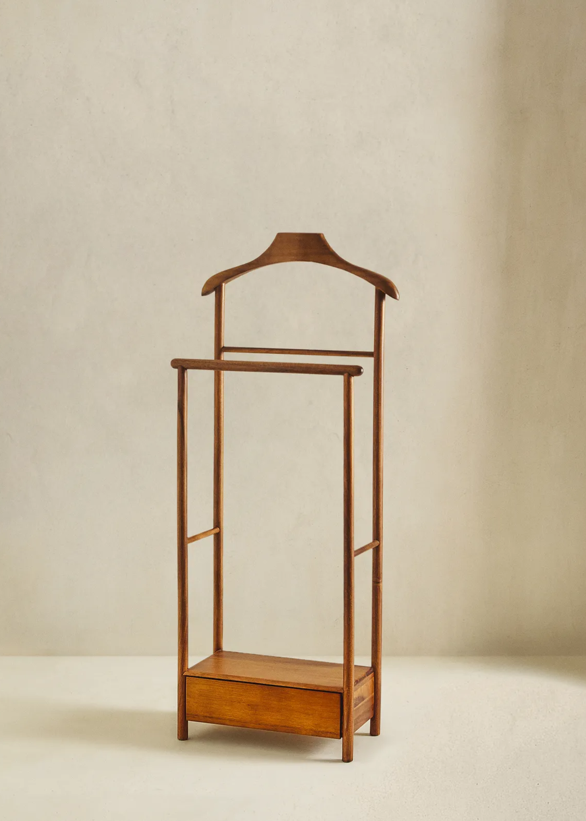 An acacia wood valet stand from Zara Home in front of a neutral wall