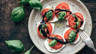 traditional italian dish of Insalata caprese surrounded by basil leaves