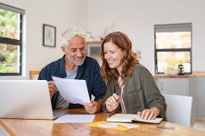 Mature smiling couple managing expenses at home. 