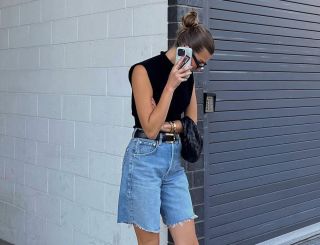 Woman on the phone wearing denim shorts, black top, and slingbacks.