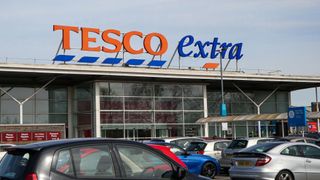 A view of the front of a Tesco Extra store with cars parked in front