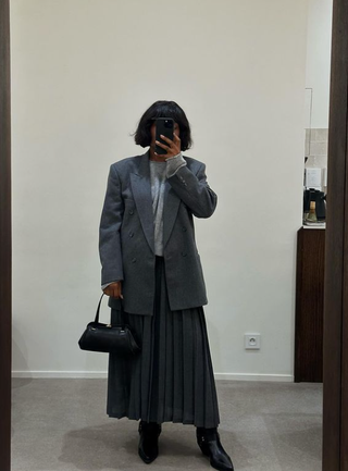 Franny wears a pleated midi skirt and ankle boots