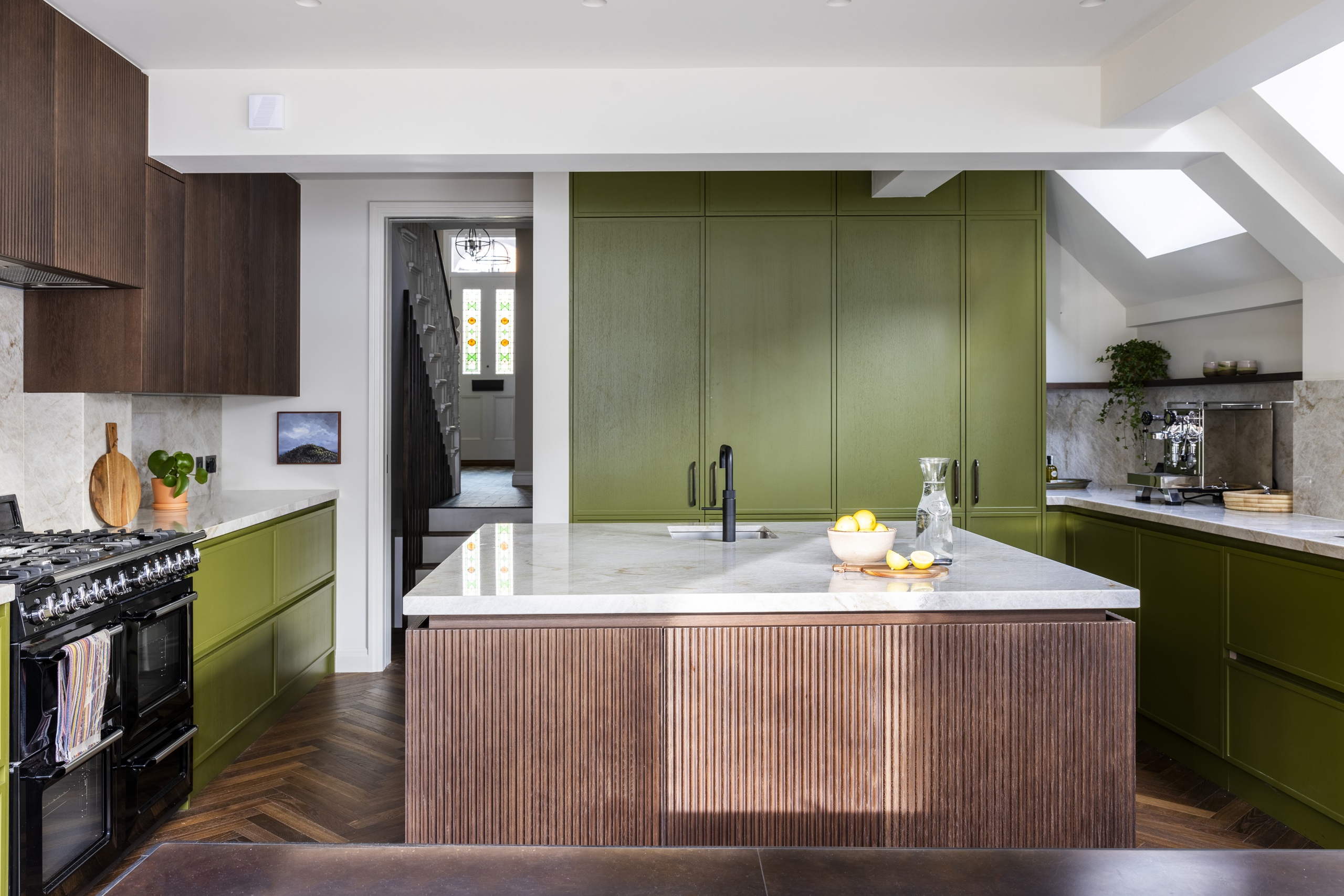 a green and fluted wood kitchen with a square island