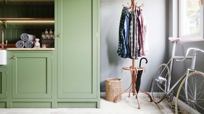 green entryway with closed storage, coat stand and bike