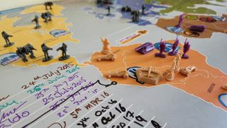 Pieces and board from the game Risk Legacy on a table