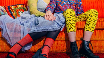 Couple in bright clothes on bright couch holding hands
