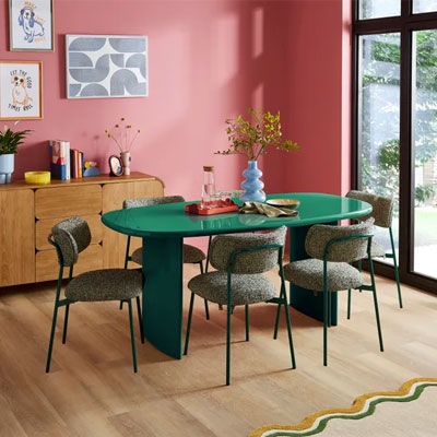 oval green dining table in pink dining room