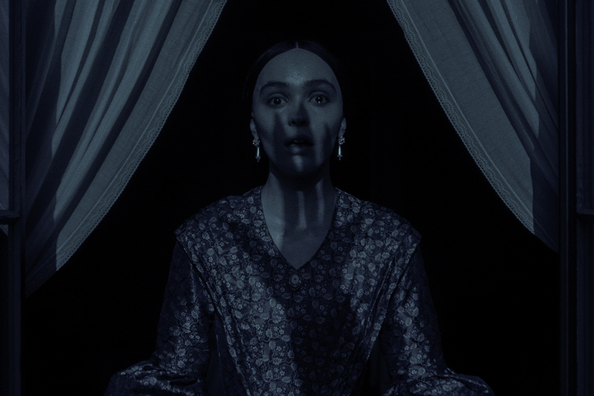 a woman (Lily-Rose Depp as Ellen Hutter) has a scared expression on her face as the shadow of a clawed hand washes over her