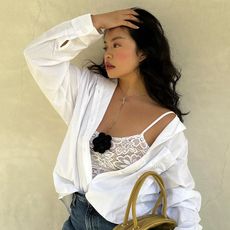 Woman wears white shirt, lace top with corsage, blue jeans