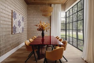 Dining room with beige metallic patterned walls, glossy red dining table and yellow chairs