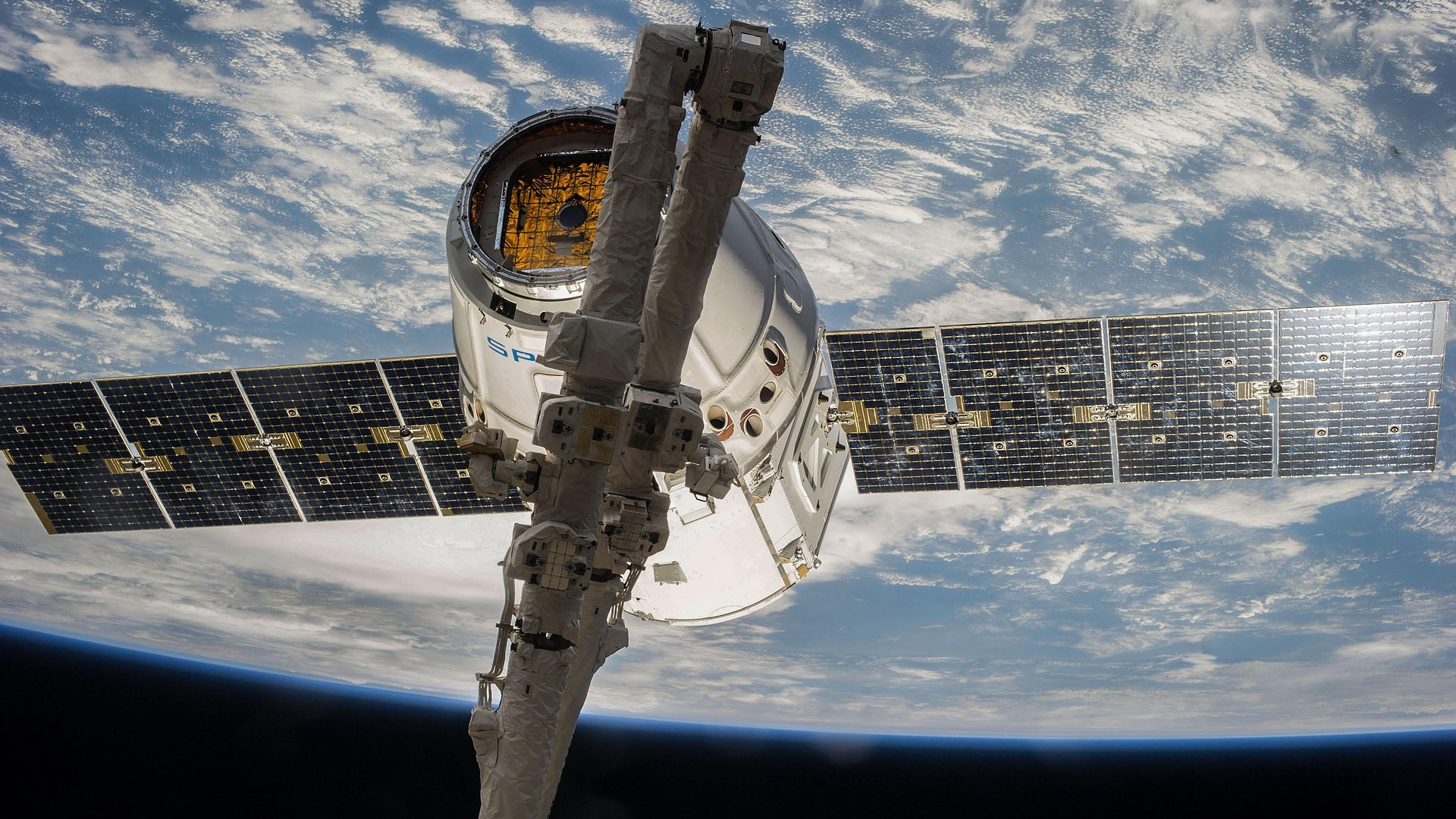 A white capsule with two solar panels is seen floating in orbit above Earth in space