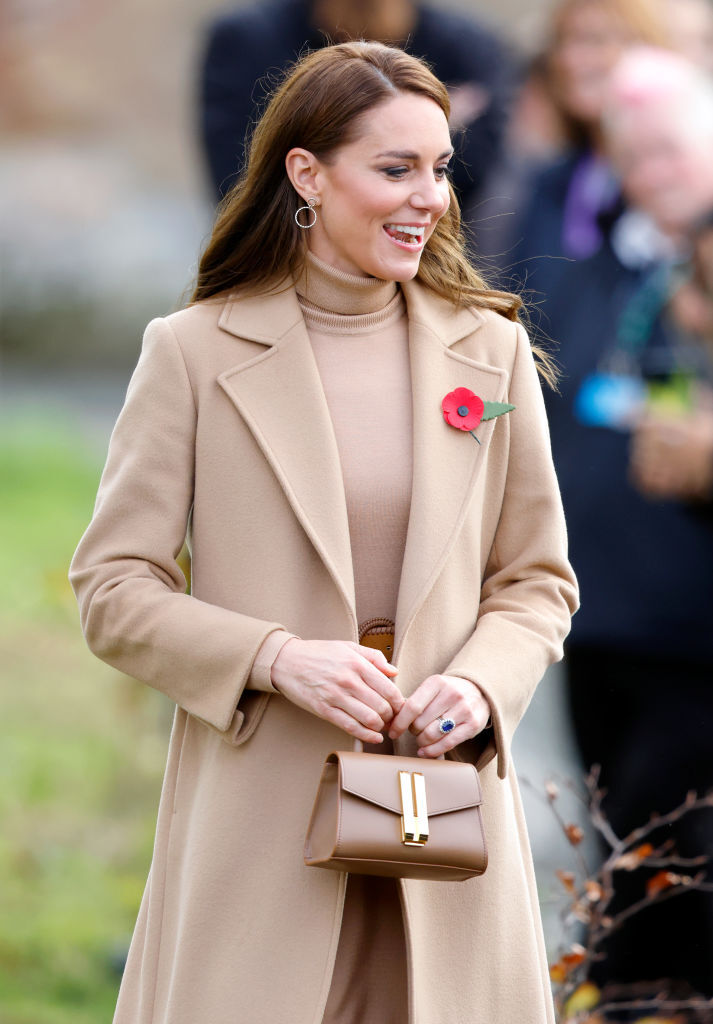 Kate Middleton wears a camel coat, camel turtleneck and carries the DeMellier nano Montreal bag