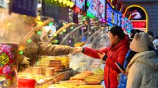 Tourists purchase food at a market in Harbin, China, during a New Year's 2025 festival.