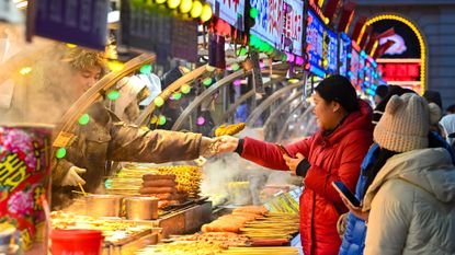 Tourists purchase food at a market in Harbin, China, during a New Year's 2025 festival.