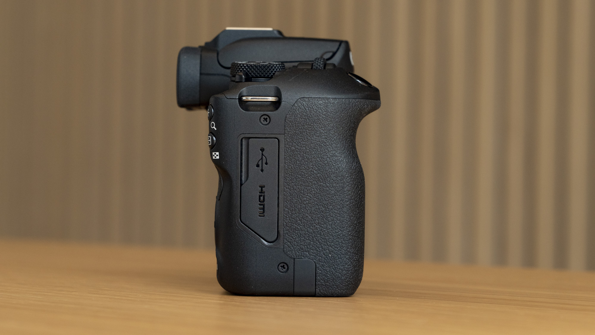 Canon EOS R100 camera on a table, right side profile