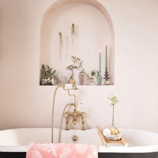 Arched alcove above bathtub styled with pretty sea inspired decorative accessories.