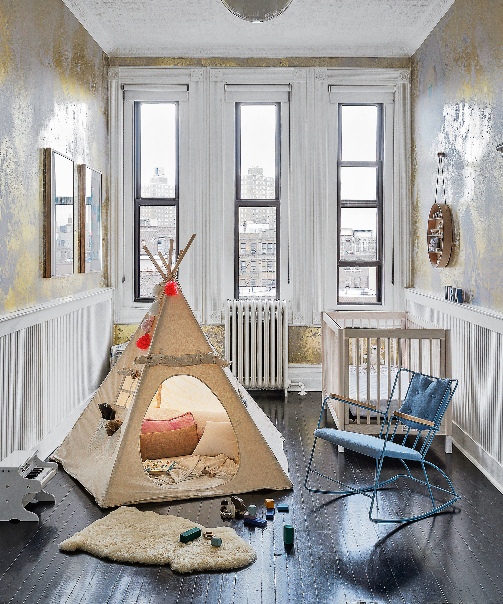 A baby boy nursery idea with metallic spray painted walls, teepee and blue armchair.