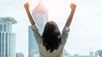 A woman raises her arms in celebration.