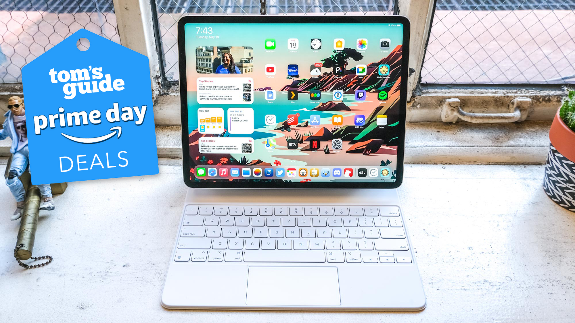 An iPad Pro 2021 docked with an Apple Magic Keyboard on a windowsill, with a Tom's Guide Prime Day Deals sticker on top