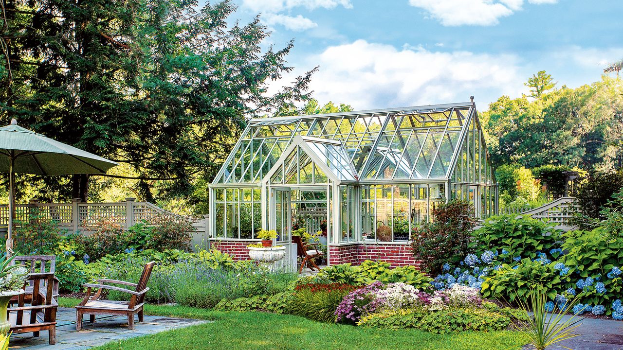 planning a greenhouse a large greenhouse surrounded by flowers and shrubbery next to an outdoor dining area