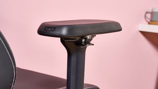 Close-up of arm on Boulies Elite next to desk with pink background