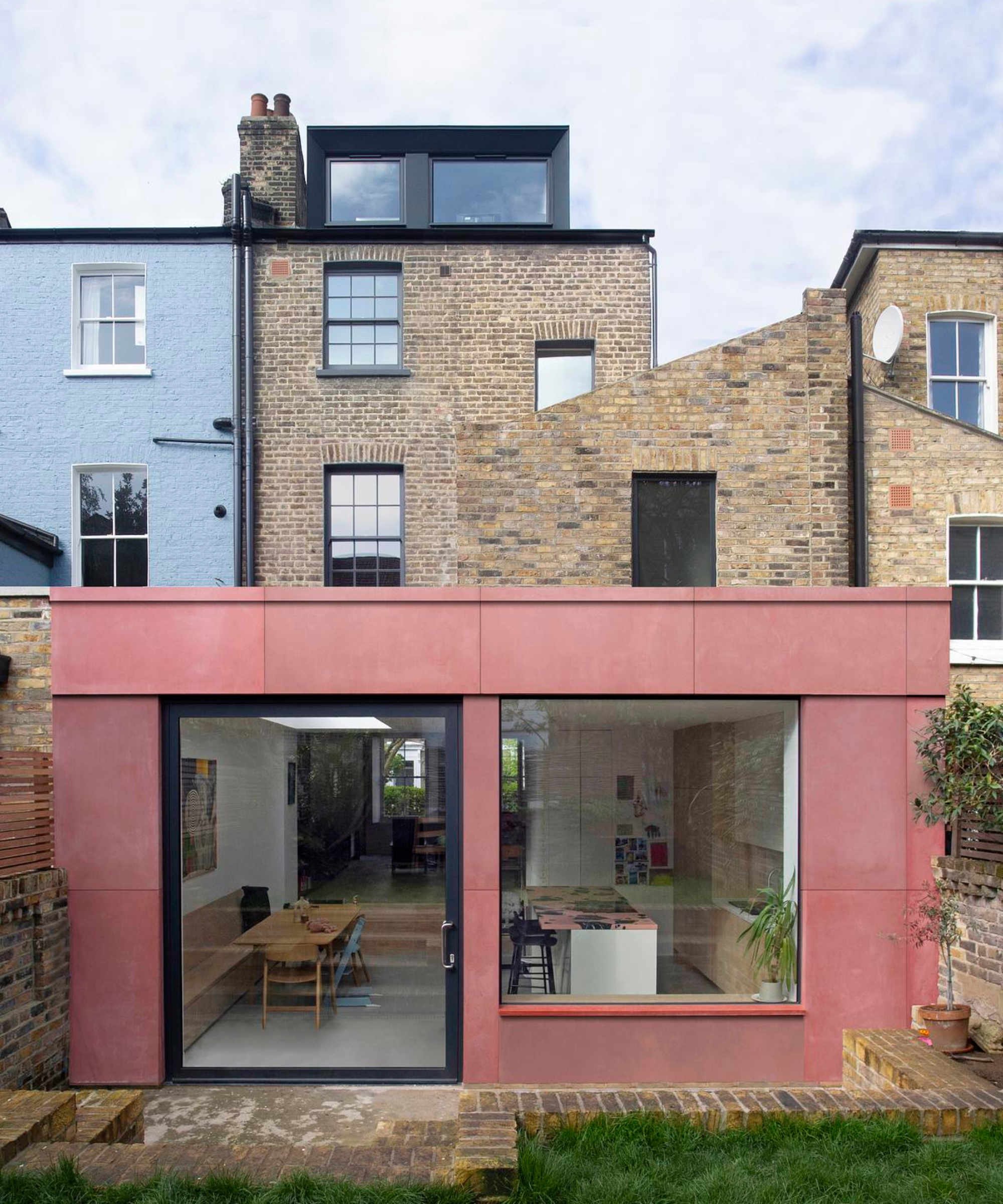 victorian terraced house with corten steel clad rear single storey extension with large picture window and pivot patio door plus black clad loft extension to top of house