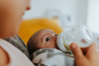 baby drinking from a glass bottle