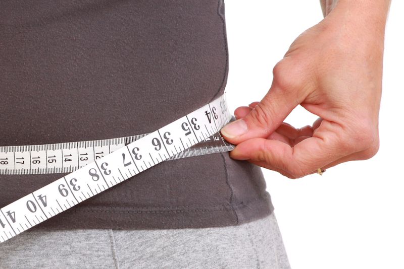 A woman measures her waistline