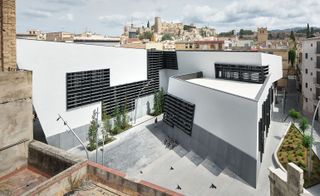 Exterior view of ’Terres de l’Ebre’ Regional Office photographed from above showcasing the black a, white and grey design of the building with other buildings in view