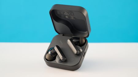 CMF Buds 2 in Dark Gray photographones on a gray table in front of a blue background