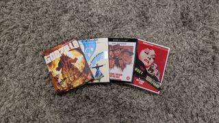 Four 4K Blu-ray cases of Godzilla, Sunset Boulevard, The Good, The Bad and The Ugly and The Sound Of Music on a carpet