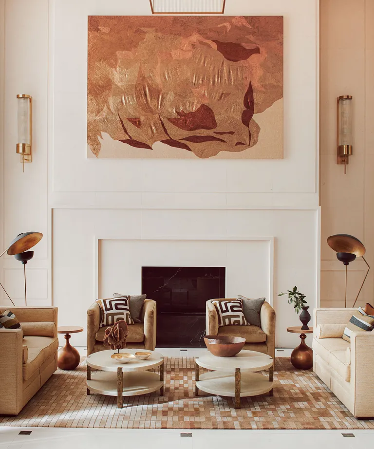 White living room with central fireplace and art with neutral seating