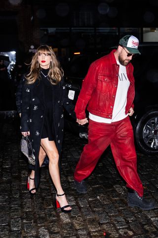 Taylor Swift in a long, crystal-embellished black coat and Travis Kelce, wearing red pants and a matching red jacket, while out in New York City on December 28, 2024