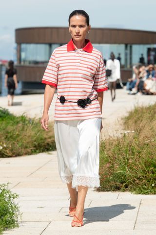 a model walks the Copenhagen Fashion Week runway wearing a red striped polo shirt